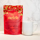 A red pouch of Nelzh Tea Organic Raspberry Green Zest, containing 20 sachets of organic raspberry and green tea blend.